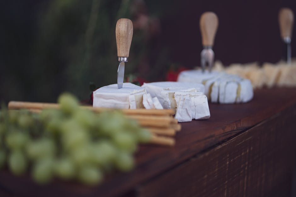 Mesa de cata de quesos artesanales con copa de vino y frutas